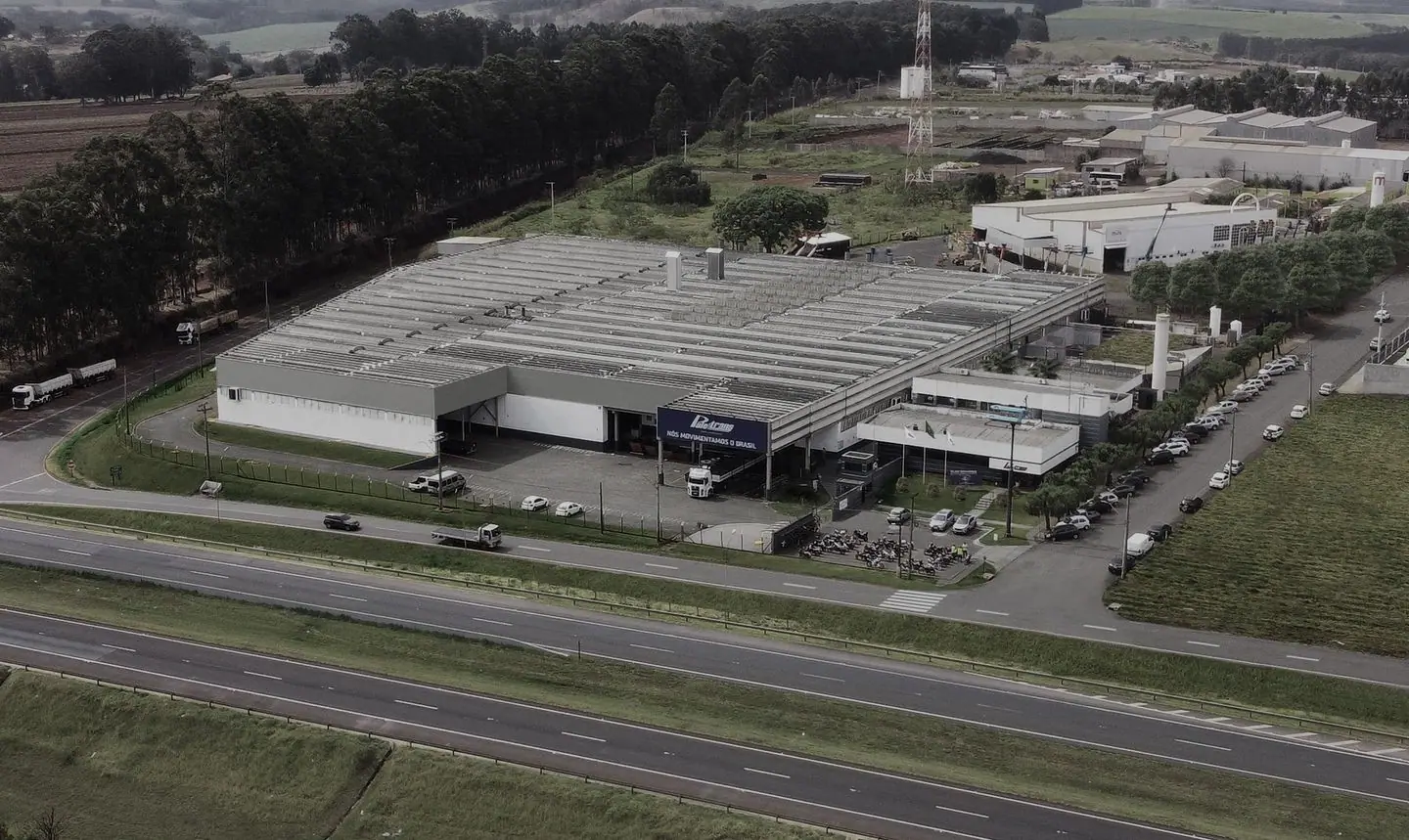 Vista aérea da fábrica da Paletrans, com a fachada "Nós movimentamos o Brasil"